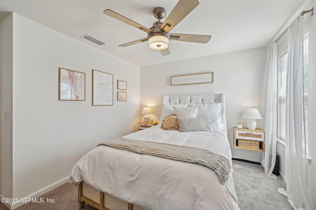 carpeted bedroom with ceiling fan and a textured ceiling