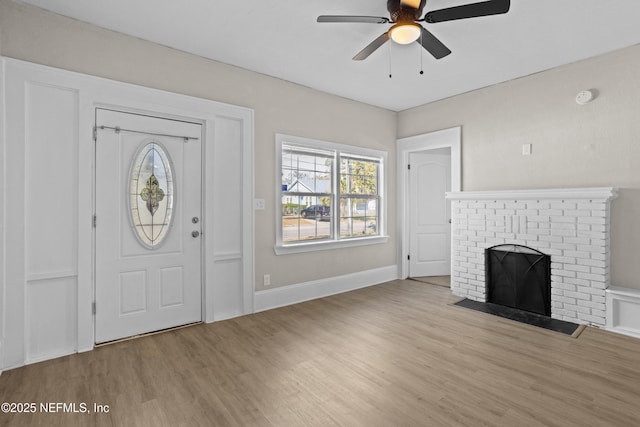 entryway with ceiling fan, light wood-type flooring, and a fireplace