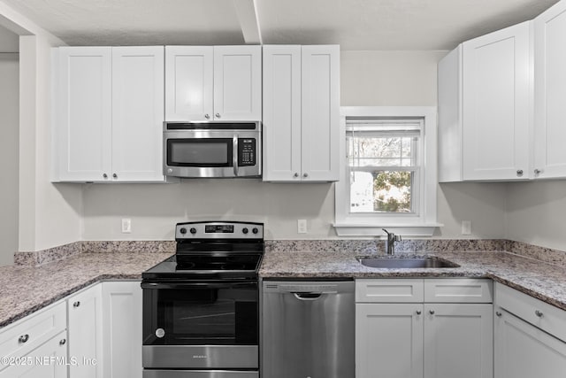 kitchen with stainless steel appliances, white cabinetry, and sink