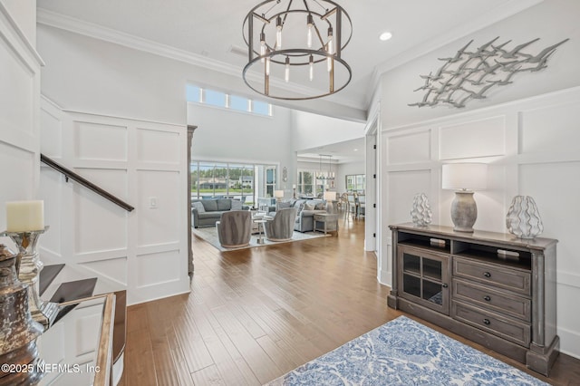 entryway with crown molding, hardwood / wood-style floors, and an inviting chandelier