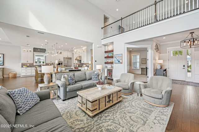 living room with a notable chandelier, dark hardwood / wood-style flooring, and a towering ceiling