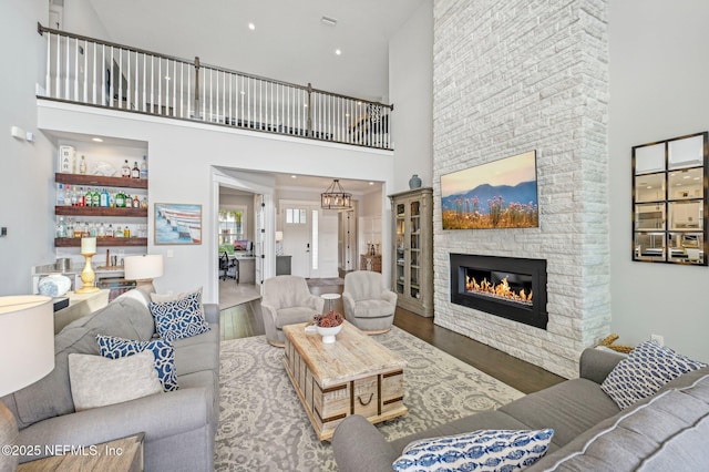 living room with a notable chandelier, dark hardwood / wood-style floors, a towering ceiling, and a fireplace