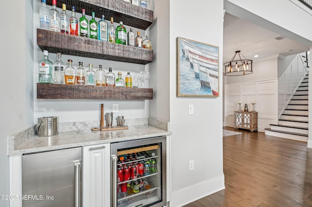 bar featuring wine cooler, light stone countertops, dark hardwood / wood-style flooring, and refrigerator