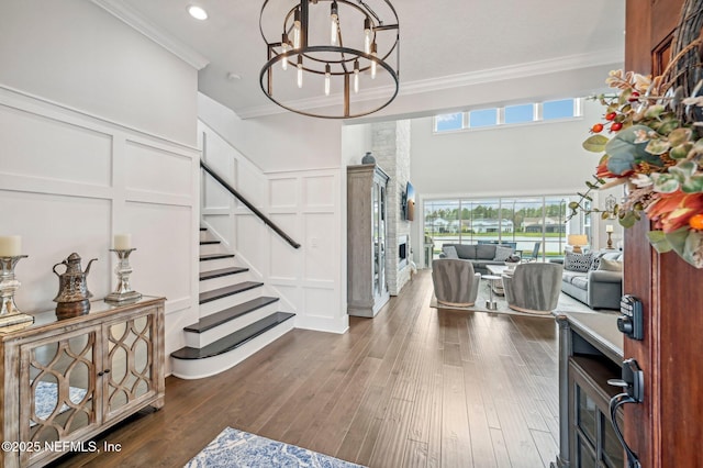 entryway with dark hardwood / wood-style floors, ornamental molding, and an inviting chandelier