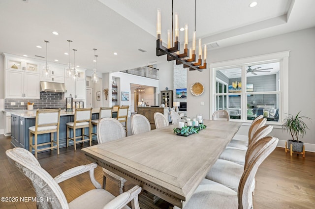 dining space with ceiling fan with notable chandelier and dark hardwood / wood-style flooring