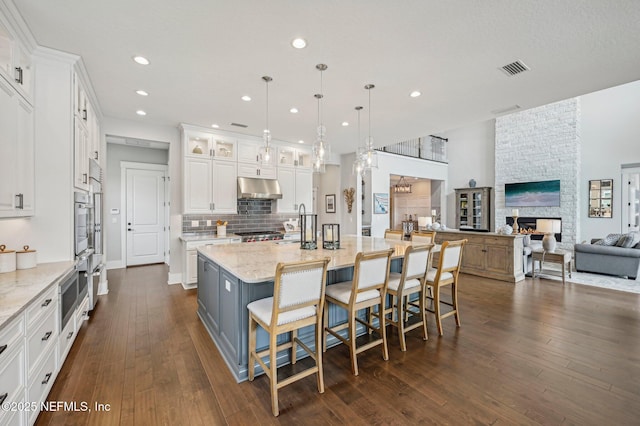 kitchen featuring white cabinetry, a fireplace, and a spacious island