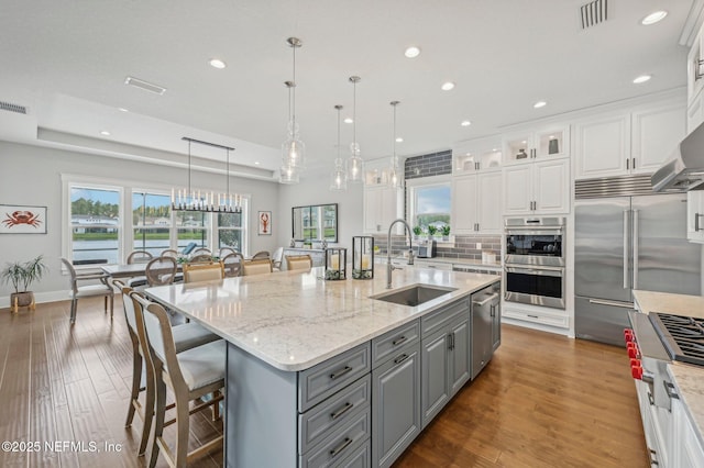 kitchen featuring gray cabinetry, white cabinetry, sink, a large island with sink, and pendant lighting