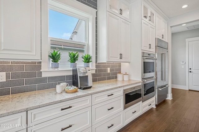 kitchen featuring light stone countertops, decorative backsplash, white cabinetry, and built in fridge