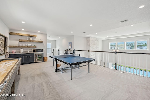 recreation room featuring a wealth of natural light, light carpet, beverage cooler, and wet bar