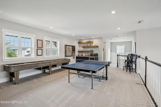 recreation room with a textured ceiling and light colored carpet