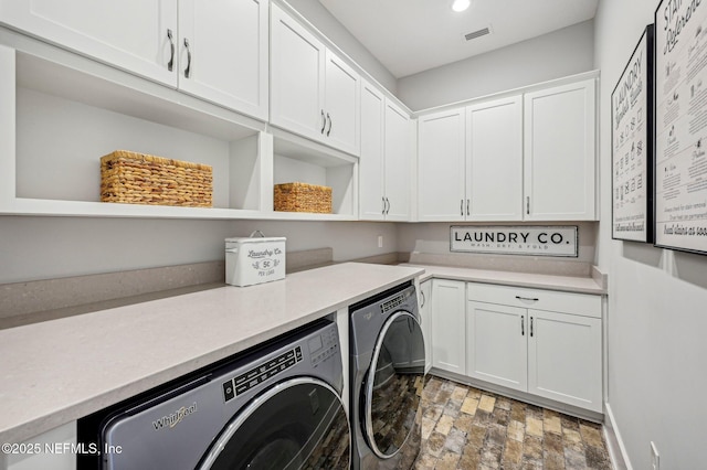 clothes washing area with cabinets and independent washer and dryer