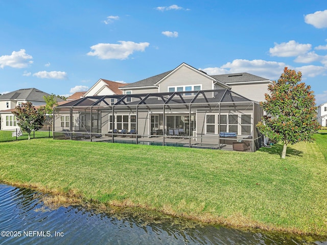 back of property with a yard, a water view, and a lanai