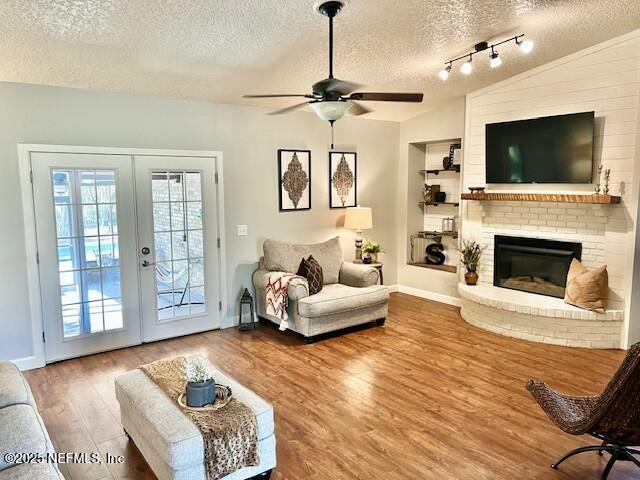 living room with a textured ceiling, ceiling fan, french doors, and lofted ceiling