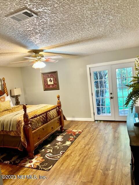 bedroom with french doors, a textured ceiling, access to outside, ceiling fan, and wood-type flooring