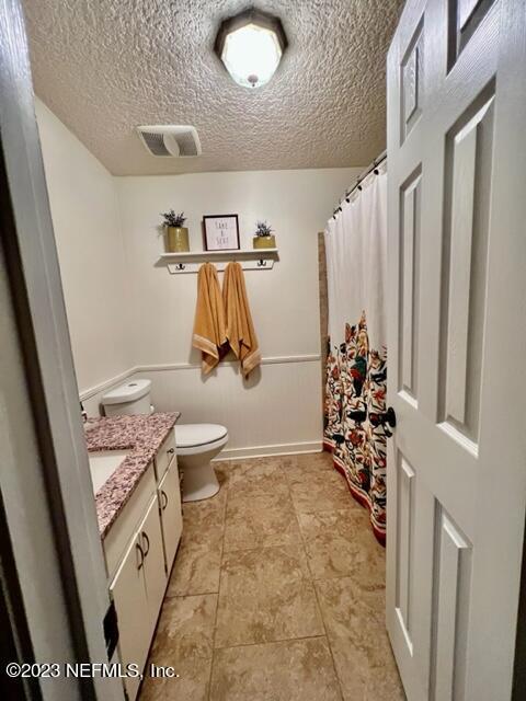 bathroom with a textured ceiling, vanity, and toilet