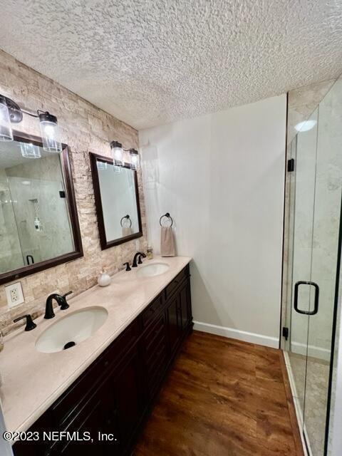 bathroom with hardwood / wood-style floors, vanity, a shower with shower door, and a textured ceiling