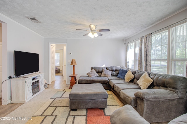 living room featuring a textured ceiling, light hardwood / wood-style floors, ceiling fan, and ornamental molding