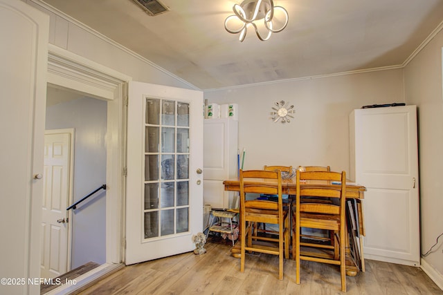 dining space featuring lofted ceiling, light wood-type flooring, and ornamental molding