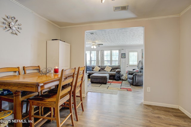 dining area featuring ceiling fan, light hardwood / wood-style floors, and crown molding