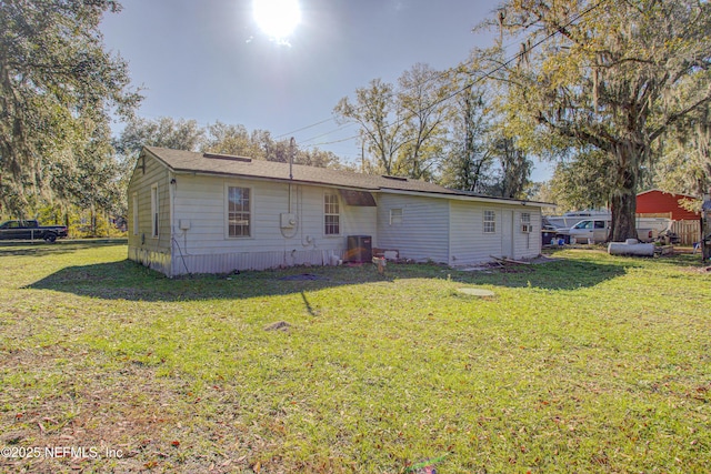 rear view of house with a lawn and central AC