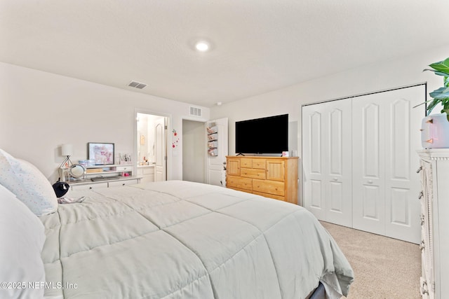 bedroom featuring light carpet, ensuite bathroom, and a closet