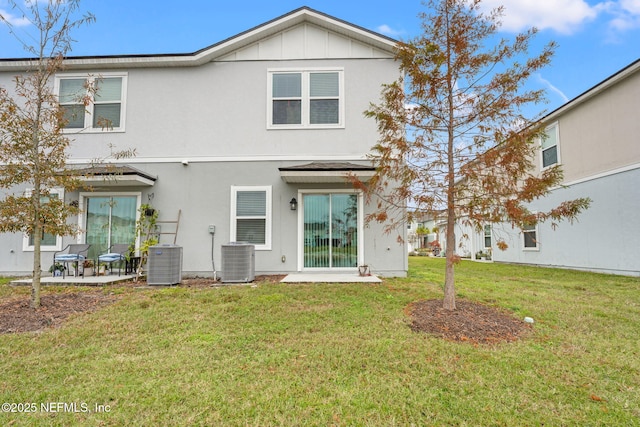 rear view of property with central AC unit and a lawn