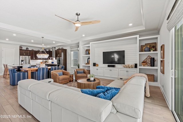 living room with ceiling fan, built in features, and crown molding