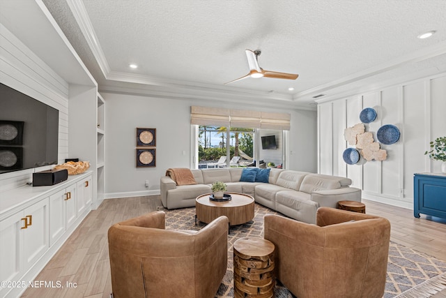 living room with a textured ceiling, ornamental molding, and light wood-type flooring