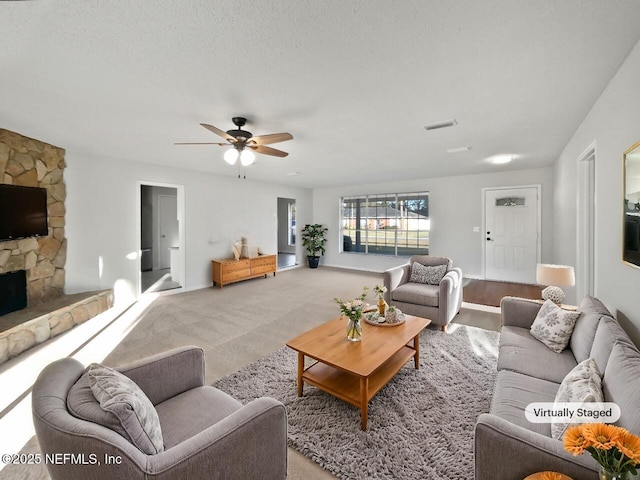 carpeted living room with a fireplace, a textured ceiling, and ceiling fan