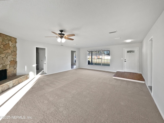 unfurnished living room featuring carpet, a fireplace, ceiling fan, and a textured ceiling