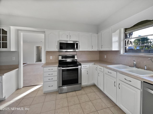 kitchen featuring white cabinets, appliances with stainless steel finishes, light tile patterned flooring, and sink