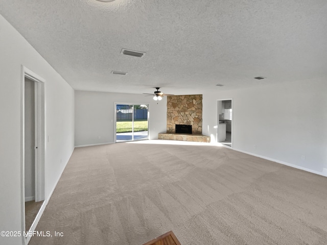 unfurnished living room featuring a stone fireplace, ceiling fan, light carpet, and a textured ceiling