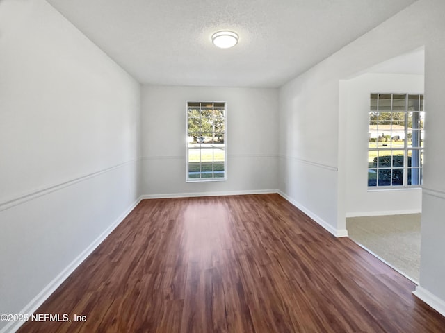 empty room with a textured ceiling and dark hardwood / wood-style flooring