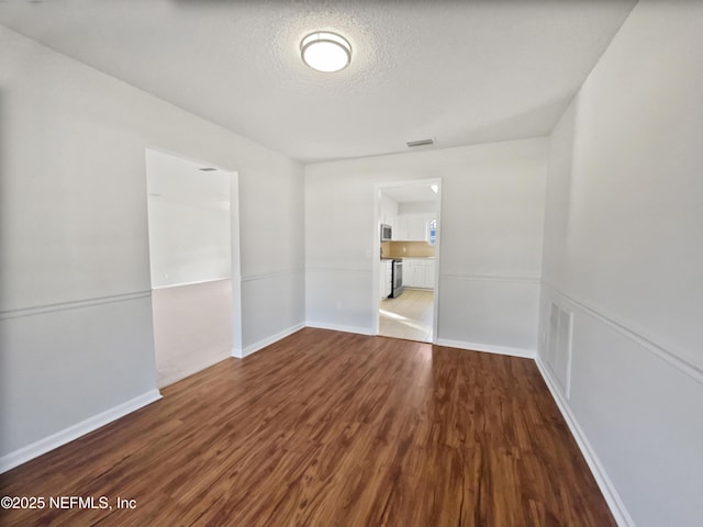 empty room featuring wood-type flooring and a textured ceiling