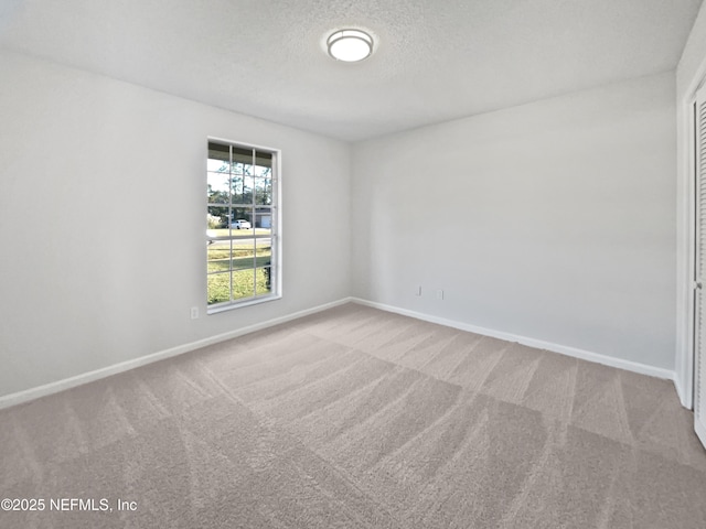 carpeted empty room featuring a textured ceiling