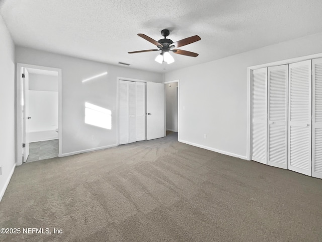 unfurnished bedroom featuring carpet, ensuite bathroom, ceiling fan, a textured ceiling, and multiple closets