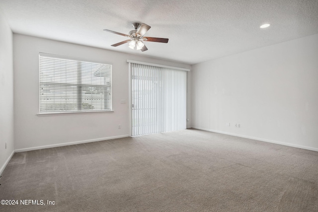 carpeted empty room with ceiling fan and a textured ceiling