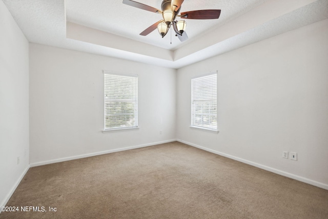 empty room featuring carpet, ceiling fan, a textured ceiling, and a tray ceiling