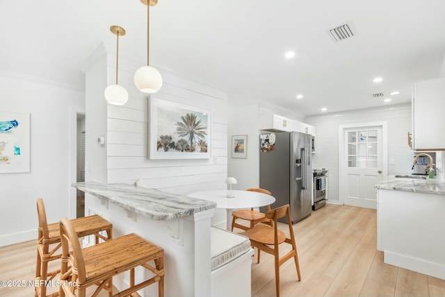 kitchen with sink, light hardwood / wood-style floors, pendant lighting, white cabinets, and appliances with stainless steel finishes