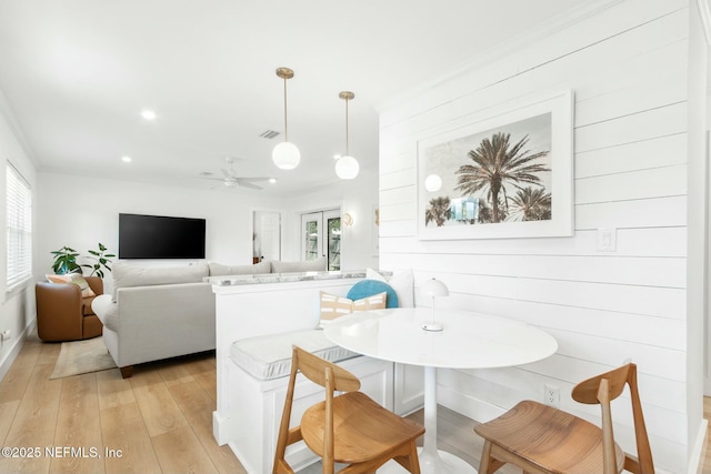 dining room featuring ceiling fan, light hardwood / wood-style floors, and wood walls