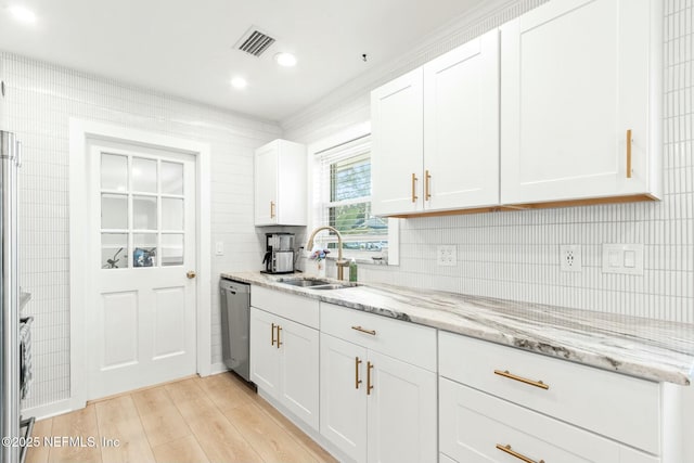 kitchen featuring white cabinets, sink, light hardwood / wood-style flooring, stainless steel dishwasher, and light stone counters