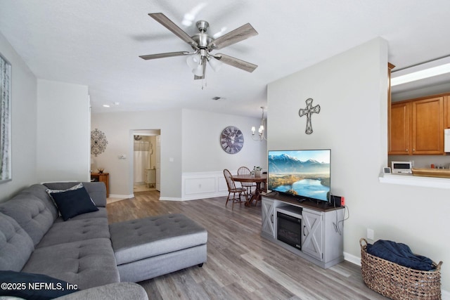 living room featuring light hardwood / wood-style flooring and ceiling fan with notable chandelier