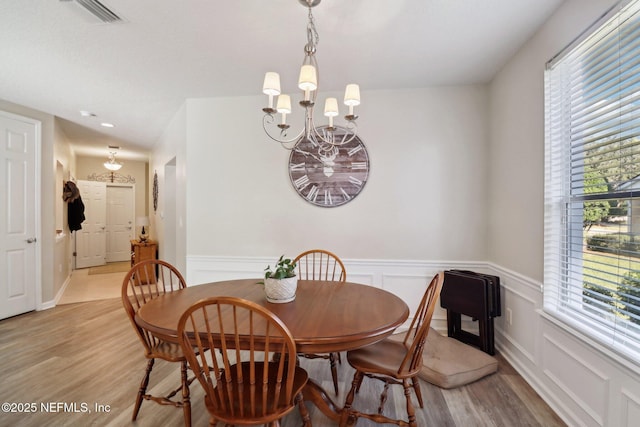 dining space featuring a healthy amount of sunlight, light hardwood / wood-style flooring, and a chandelier