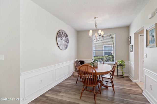 dining room with wood-type flooring, a textured ceiling, and an inviting chandelier