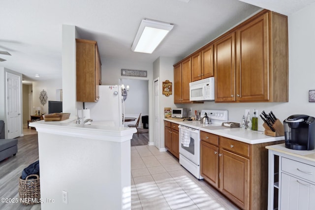 kitchen with white appliances, kitchen peninsula, and light tile patterned floors