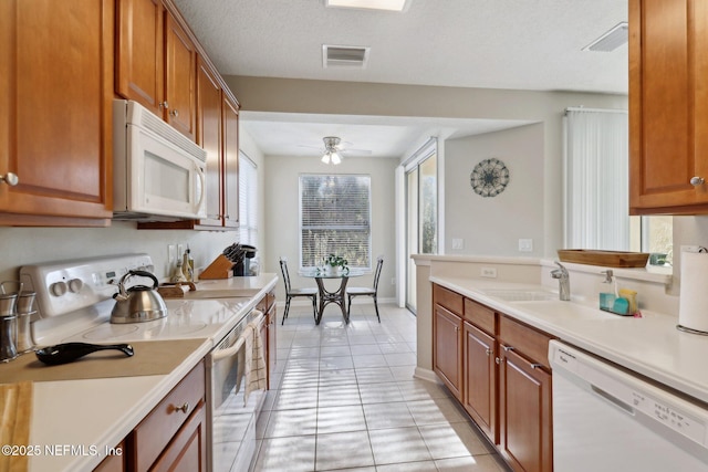 kitchen with ceiling fan, sink, a textured ceiling, white appliances, and light tile patterned floors