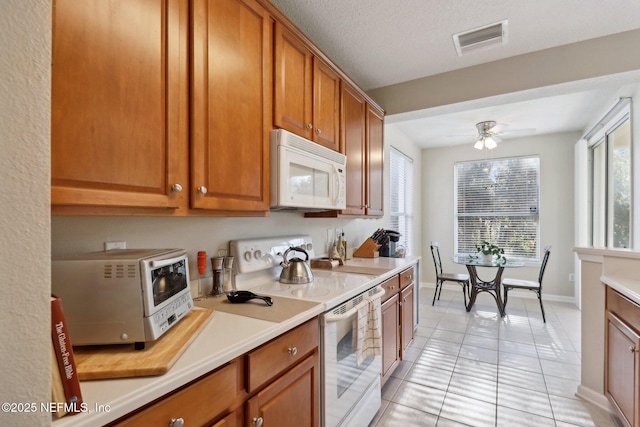 kitchen with a textured ceiling, white appliances, ceiling fan, and light tile patterned flooring