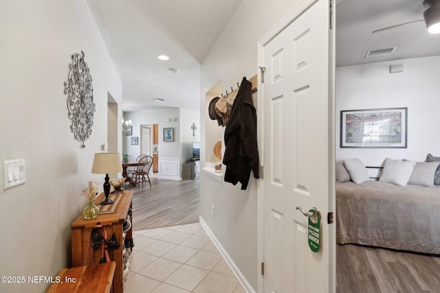 corridor featuring light tile patterned floors and a textured ceiling