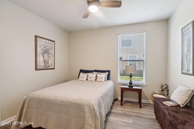 bedroom featuring ceiling fan, light hardwood / wood-style floors, and multiple windows