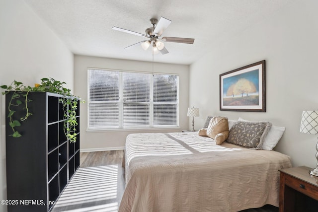 bedroom featuring ceiling fan, light wood-type flooring, and a textured ceiling